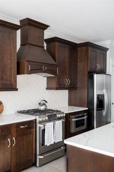 a kitchen with wooden cabinets and stainless steel appliances, including an oven hood over the range