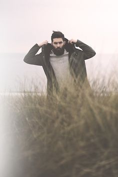 a man standing in tall grass with his hands on his head