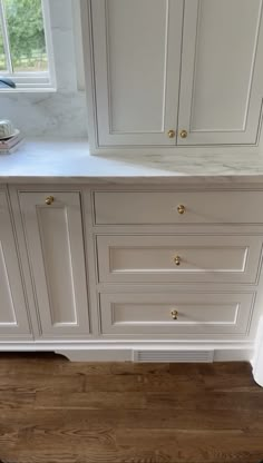 a kitchen with white cabinets and wood floors