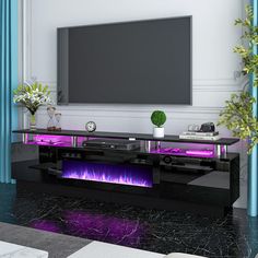 an entertainment center with purple lights and a flat screen tv mounted on the wall above it