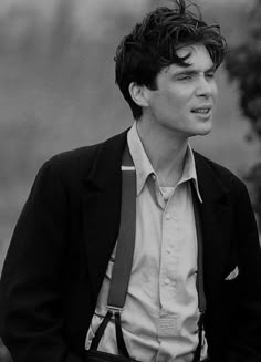 black and white photograph of a young man wearing a suit with suspenders on his lap