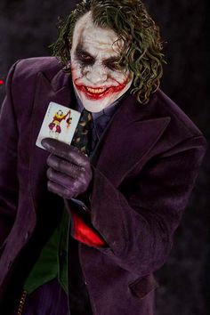 a man dressed as the joker holding a card