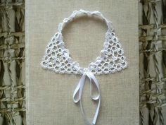 a white lace collar on top of a piece of cloth with a ribbon tied around it