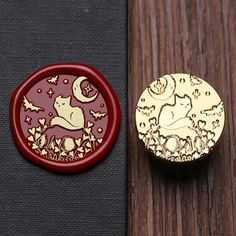 a red and gold brooch sitting on top of a wooden table next to a button