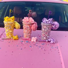 three ice cream sundaes sitting on the hood of a car with confetti and sprinkles