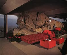 a living room filled with red furniture and large rocks