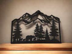 a metal mountain scene with trees and an elephant in the foreground on a wooden shelf