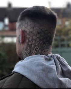 the back of a man's head with tattoos on his face and neck is shown