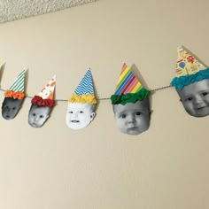 a group of paper hats hanging from a line with pictures on the clothes pegs