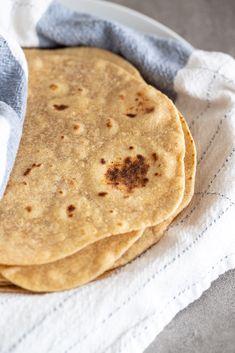 three tortillas sitting on top of a white plate next to a blue and white towel