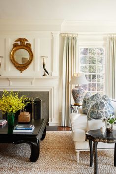 a living room filled with furniture and a fire place in front of a mirror on the wall