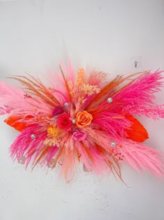 an orange and pink feather headpiece with flowers on it's side, against a white background