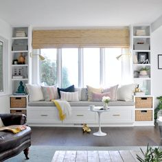 a living room filled with furniture and lots of windows covered in white walls, along with bookshelves