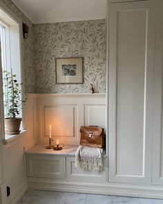 a room with a bench, candle and potted plant in the window sill