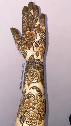 a hand with henna on it and flowers painted on the palm is shown in front of a white wall