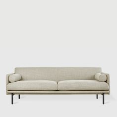 a white couch sitting on top of a wooden floor next to a gray wall in front of it