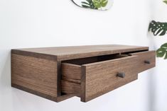 a close up of a wooden drawer on a wall with a plant in the background