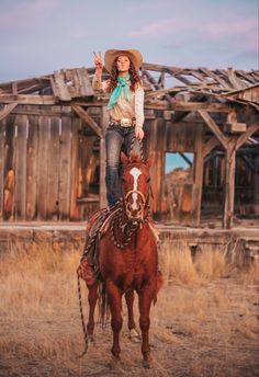 a woman riding on the back of a brown horse in front of a wooden building