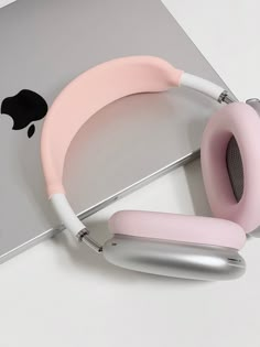 the pink headphones are next to an apple laptop on a white table with silver and gray accessories