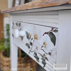 an old dresser painted with white flowers and green leaves