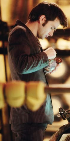 a man standing in front of a table holding a wine glass and looking at it