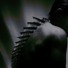 the back of a woman's body with spikes on her head and shoulders, in black and white