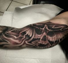 a man's arm with a skull and wings tattoo on it