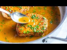 two pieces of meat are being spooned into a pot of soup with parsley on top