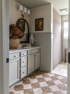 a bathroom with a checkered floor and white cabinets