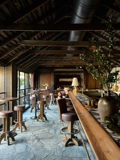 a bar with several stools and tables in the middle of an indoor area that looks like a log cabin