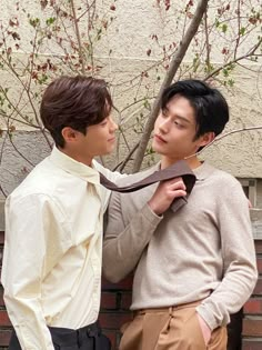 two young men standing next to each other with ties around their necks and looking at each other