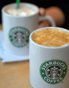 two starbucks coffee cups sitting on top of a table