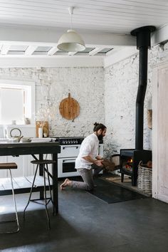 a man kneeling down in front of an open fire place next to a kitchen counter