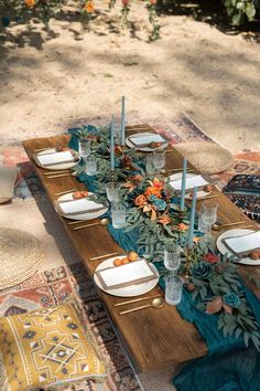 an outdoor table set with plates and place settings for dinner on a rug in the sun