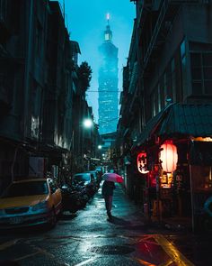 a person with an umbrella is walking down the street in the city at night time