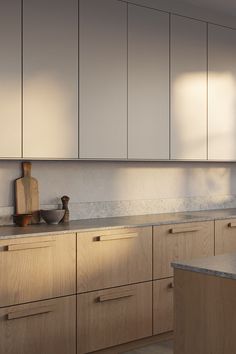 an empty kitchen with wooden cabinets and counter tops in the daytime light, along with a cutting board on the counter