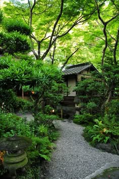 a small house surrounded by lush green trees and rocks in the middle of a garden