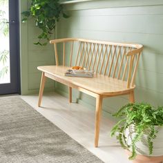 a wooden bench sitting next to a potted plant on top of a white rug