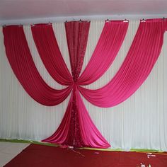 pink and white drapes are hanging on the wall in front of a red carpet