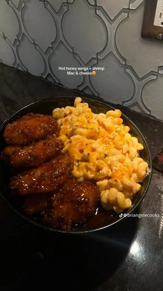 some food is in a black bowl on a table next to a wallpapered wall