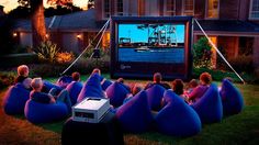 people sitting on bean bag chairs watching a movie in front of a house at night