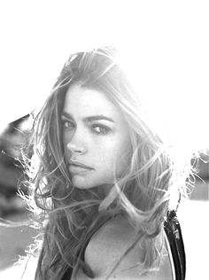 a black and white photo of a woman with her hair blowing in the wind