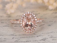 an oval shaped pink diamond surrounded by smaller round diamonds on top of a floral background