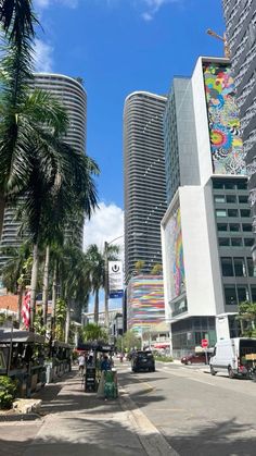 a city street with tall buildings and palm trees