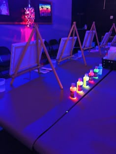 several lit candles sit on top of a table in front of easels and paintings