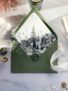 a green envelope with trees on it and some gold coins next to it, along with other christmas decorations