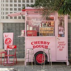 a pink food truck parked on the side of a road next to a palm tree