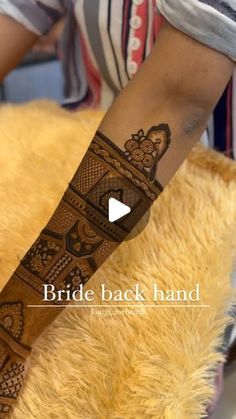 a person with a henna tattoo on their arm and leg, sitting next to a teddy bear