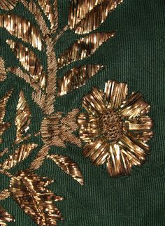 gold flowers on green fabric with golden threadwork and sequins in the center