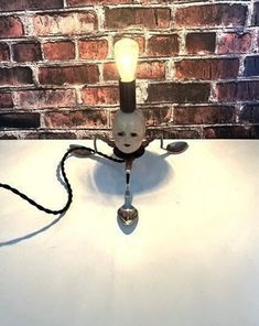 a table lamp that is on top of a white surface with a brick wall in the background